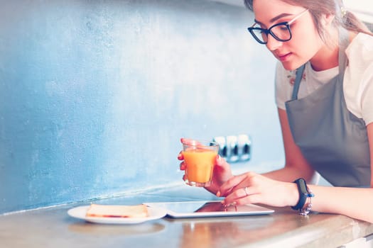 Attractive woman holding a glass of orange juice while standing in the kitchen.