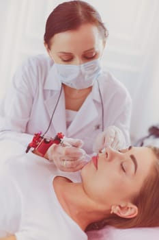 A young girl having red lips permanent makeup, micropigmentation.