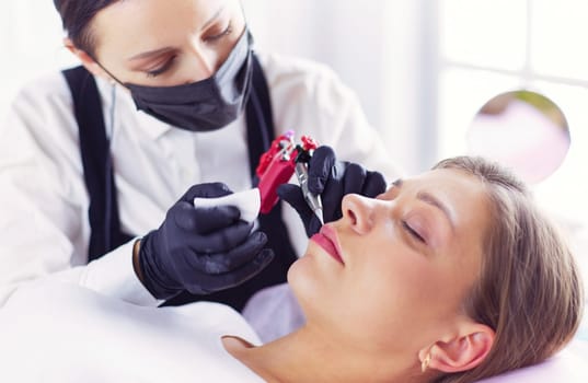 Cosmetologist applying permanent make up on eyebrows.