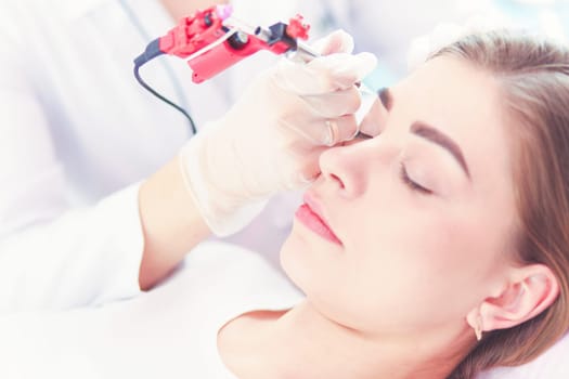 A young girl having red lips permanent makeup, micropigmentation.