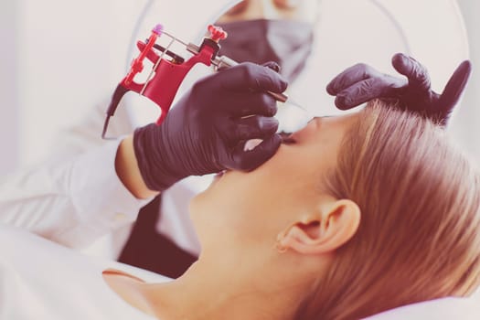 Microblading eyebrows work flow in a beauty salon. Woman having her eye brows tinted.