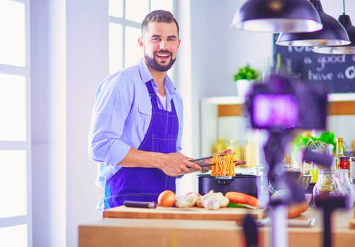 Man holding paper bag full of groceries on the kitchen background. Shopping and healthy food concept.