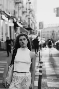 A classy girl with curly hair dressed in white on the city streets. High quality photo