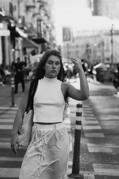 A fashionable girl in white attire with curly hair on the city streets. High quality photo