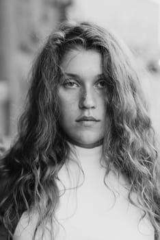 A black and white portrait of a stylish young girl with curly hair. High quality photo