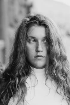 A monochrome portrait of a fashionable young girl with curly hair. High quality photo