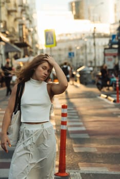 A classy girl with curly hair dressed in white on the city streets. High quality photo