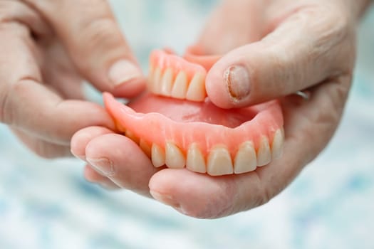 Asian elderly woman patient holding to use denture, healthy strong medical concept.