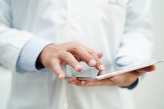 Asian man doctor using tablet computer to reading patient report, check up and search for solve treatment health medical online in hospital.