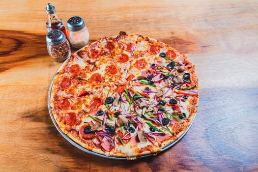 High angle view of mixed supreme pizza on wooden table. Top view of a supreme mixed pizza on wooden table