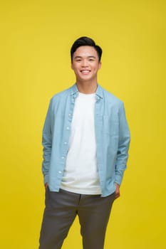 Young man wearing white t-shirt and blue jeans in yellow color isolated studio background