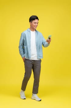 Adult Asian man walking relax while looking to the camera and holding mobile phone