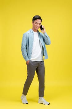 Happy smiling man in jeans and denim shirt talking on the phone looking at camera. 