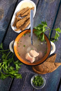 top view of hot soup fish soup with red fish and greens on a wooden table.