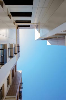 Exterior of a new multi-storey building. Angle from below on the view of the house and the sky.