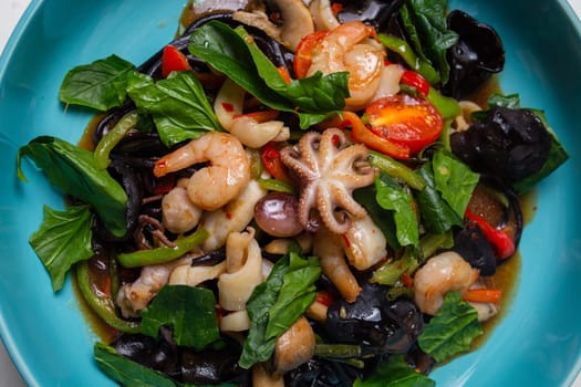close-up salad with seafood and black mushrooms in a blue plate top view.