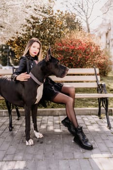 A woman walks with her Great Dane in an urban setting, enjoying the outdoors and the company of her dog