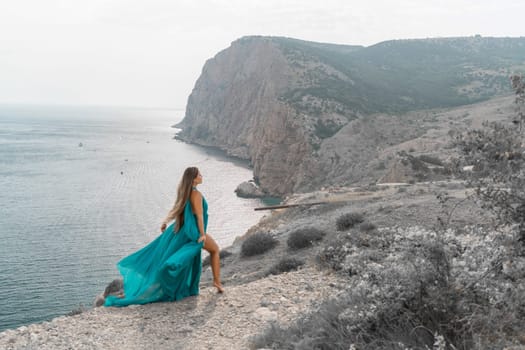 Woman sea green dress. Side view a happy woman with long hair in a long mint dress posing on a beach with calm sea bokeh lights on sunny day. Girl on the nature on blue sky background