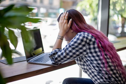 Rear shot of female student learning online via laptop before her lectures. Woman typing on notebook with blank screen, sitting at wooden table