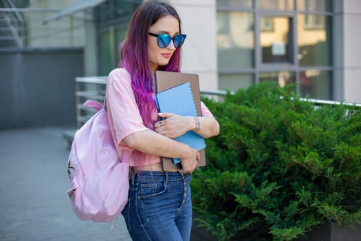 Portrait beautiful female writer dressed in casual outfit holding modern laptop in hand with backpack. Young student of faculty journalism having good mood outdoor