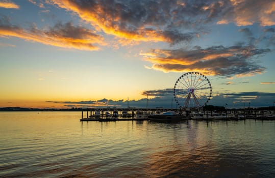 Illuminated ferris wheel at National Harbor near the nation capital of Washington DC at sunset with marina in the foreground