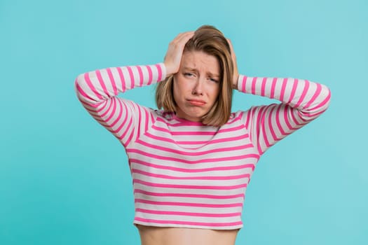 Sad woman feeling hopelessness loneliness, nervous breakdown, loses becoming surprised by lottery results, bad fortune, loss unlucky news. Young girl in crop top isolated on studio blue background