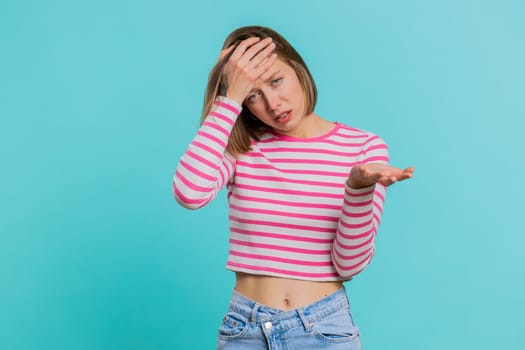 Face palm. Shame on you. Upset Caucasian young woman making face palm gesture, feeling bored, disappointed in result, bad news, sorrowful. Unhappy girl isolated on blue studio background indoors