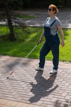 Blind pregnant woman walking in the park with a cane