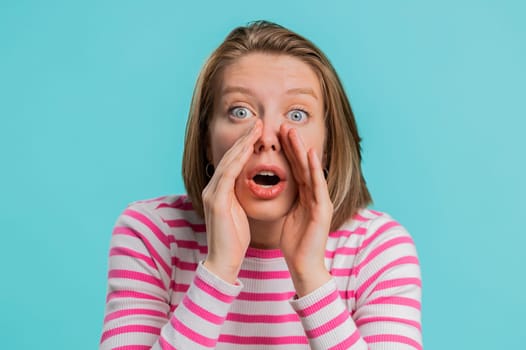 Keep my secrets, silence. Woman whisper news rumors holding hands near mouth share gossip, quiet. Girl in crop top telling interesting confidential story isolated on blue studio background. Lifestyles