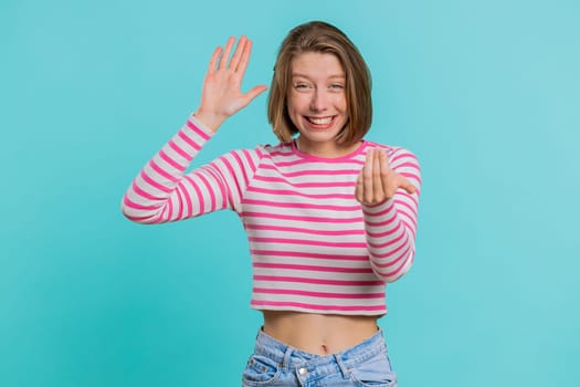Come here, join us. Welcome. Attractive woman in crop top showing inviting gesture with hands, ask to join, beckoning to coming, gesturing hello goodbye. Pretty girl isolated on blue studio background