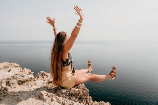 Woman travel sea. Happy tourist taking picture outdoors for memories. Woman traveler looks at the edge of the cliff on the sea bay of mountains, sharing travel adventure journey.