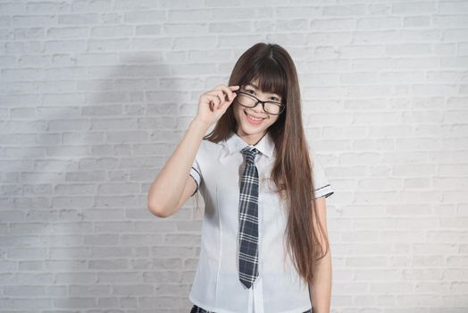 Portrait of cute student girl wearing japan uniform on gray background