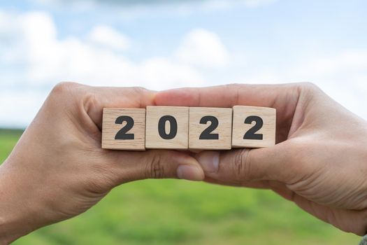 Hand hold wooden cubes 2022 background, copy space. Goal concept, action plan, strategy, new year or business vision. 
