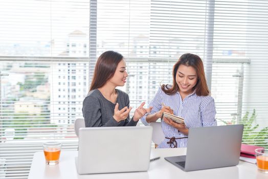 Happy young businesswoman talking to her colleague