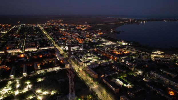 The embankment of a small town at sunset. There are attractions, a small green park. Cars are passing by. People are resting and walking. Near Lake Balkhash. View of the evening city. Kazakhstan