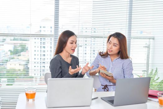 business, teamwork and people concept - female team or businesswomen with laptop computer working at office