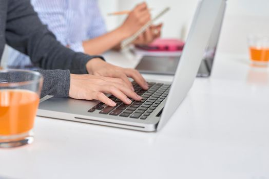 business, teamwork and people concept - female team or businesswomen with laptop computer working at office