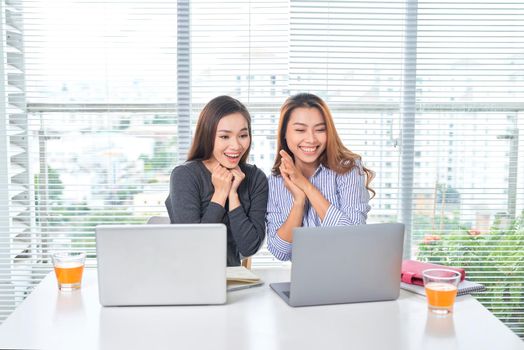 business, teamwork and people concept - female team or businesswomen with laptop computer working at office