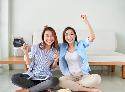 Happy girl friend watching tv at home.