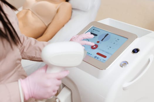 Therapist checking laser hair removal machine at aesthetic clinic. Woman beautician using laser epilation machine in beauty salon.