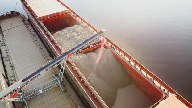 Grain loading in hold of bulk carrier ship with elevator crane closeup. Port grain elevator. download photo
