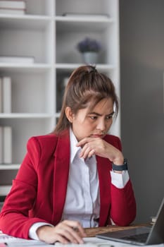 Young Asian businesswoman working on laptop computer, stressed has a headache and thinks hard from work at the office...