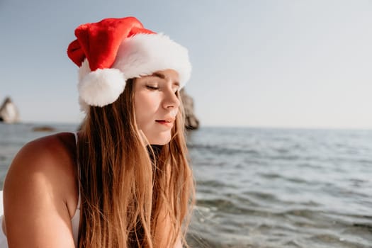 Close up shot of happy young caucasian woman looking at camera and smiling. Cute woman portrait in bikini posing on a volcanic rock high above the sea