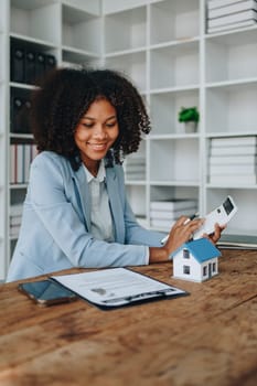 Real estate agent, African American businesswoman Africans use smartphone and calculators to offer mortgages to their clients. Home mortgage and insurance finance concepts