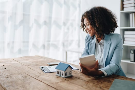 Real estate agent, African American businesswoman Africans use smartphone and calculators to offer mortgages to their clients. Home mortgage and insurance finance concepts