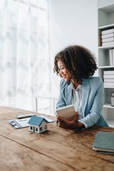 Real estate agent, African American businesswoman Africans use smartphone and calculators to offer mortgages to their clients. Home mortgage and insurance finance concepts