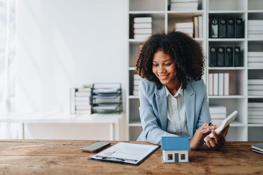 Real estate agent, African American businesswoman Africans use smartphone and calculators to offer mortgages to their clients. Home mortgage and insurance finance concepts