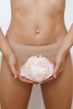 Brazilian bikini epilation. Woman with rose showing smooth skin on white background, closeup.