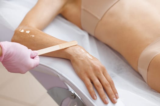 Close up of cosmetologist in sterile gloves applying ultrasound gel on female hand before epilation. Laser hair removal and cosmetology. Preparing woman skin for laser hair removal treatment in salon.
