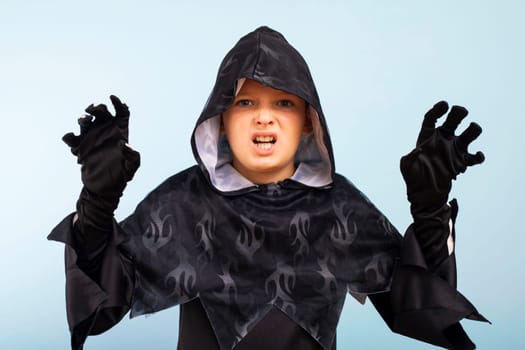 Portrait of an angry little boy in a wizard costume on a blue background. Happy Halloween holiday